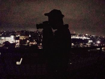 Silhouette man and illuminated cityscape at night