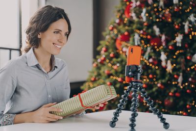 Portrait of young woman holding christmas tree