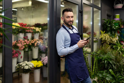 Portrait of young man standing in greenhouse