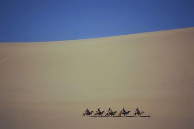Group of people on desert against clear sky