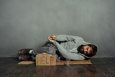 Young man lying on floor against wall at home