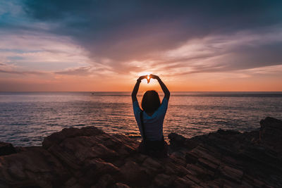 Rear view of man in sea against sky during sunset