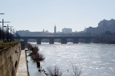 Bridge over river in city against clear sky