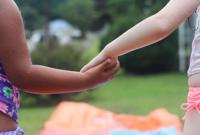 Midsection of children holding hands at yard