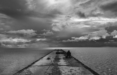 Rear view of men standing at beach against sky