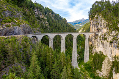 Arch bridge against trees and mountains