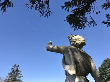 Low angle view of angel statue against clear blue sky