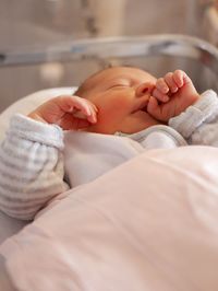 Close-up of newborn lying on bed at hospital