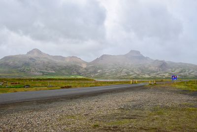 Road leading towards mountains against sky