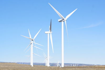 Windmills on field against clear sky