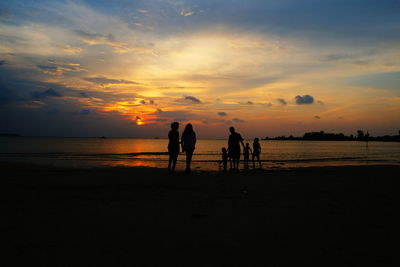 Silhouette people on beach against sky during sunset