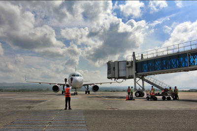 Airplane on airport runway against sky