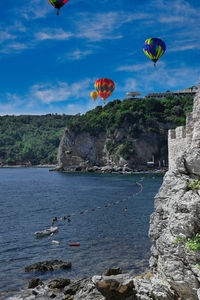 Hot air balloons flying over sea against sky