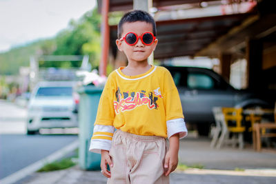 Boy wearing sunglasses standing by car