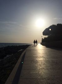 Silhouette people on beach against sky during sunset