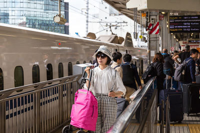 Woman with umbrella standing on railing in city