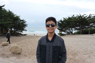 Portrait of smiling boy standing at beach against sky