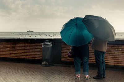 Couple in front of the sea under an umbrella on a rainy day