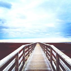Empty wooden pier against cloudy sky