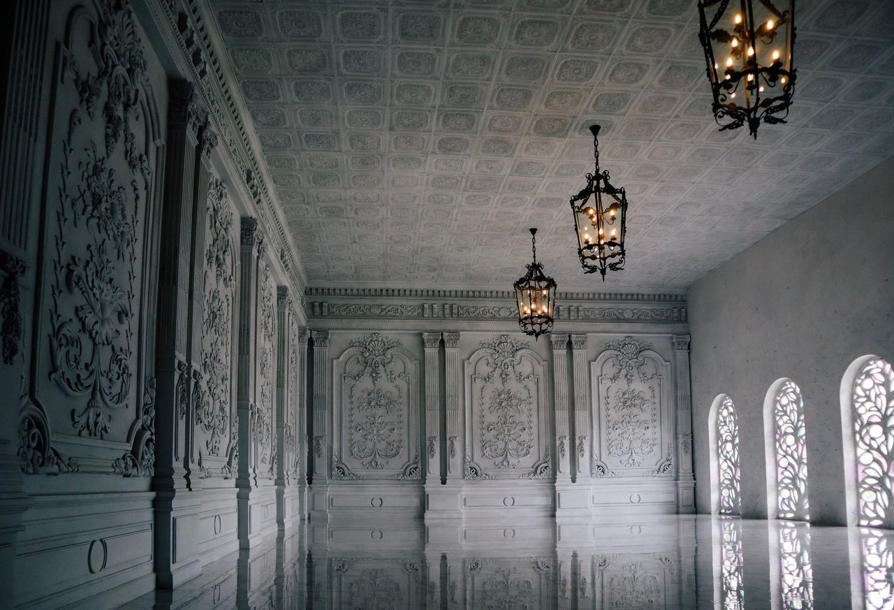 LOW ANGLE VIEW OF ILLUMINATED CHANDELIER HANGING ON CEILING IN BUILDING