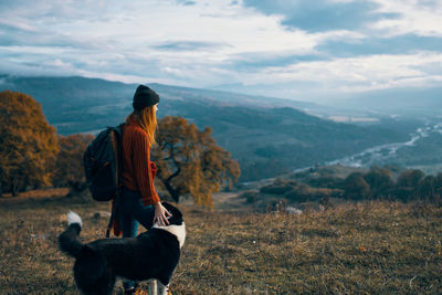 Rear view of woman with dog looking at mountains