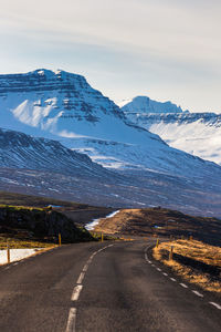 Road amidst snowcapped mountains against sky