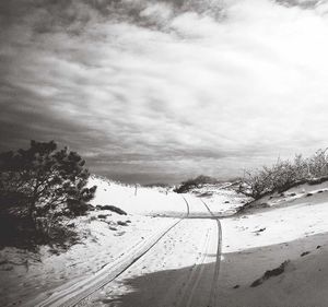 Snow covered road by trees against sky