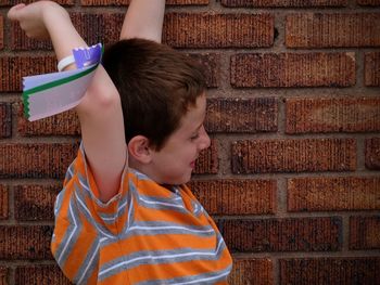 Boy with label on hand against brick wall