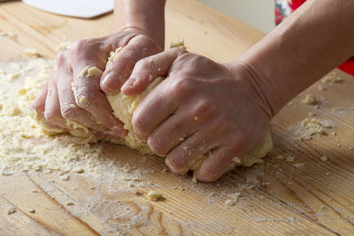 Cropped hands preparing pasta dough on table