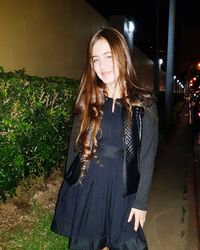 Smiling young woman standing outdoors at night