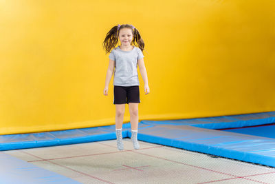 Portrait of girl standing against yellow wall