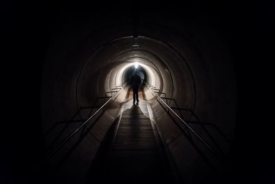 Rear view of man walking in tunnel