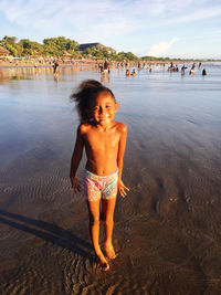 Rear view of shirtless young woman standing in lake