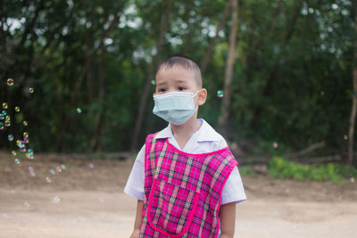 Boy wearing mask looking away standing outdoors