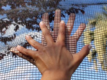 Cropped hands touching fence