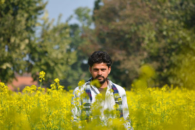 Young indian farmer at black mustard field