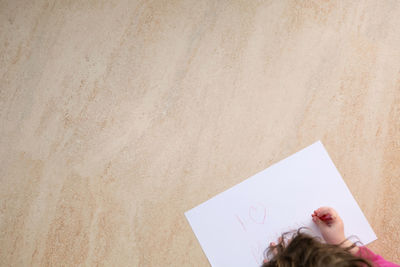 High angle view of woman holding paper against wall