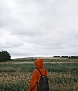 Rear view of man standing on field against sky