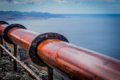 Close-up of rusty pipe by sea against sky