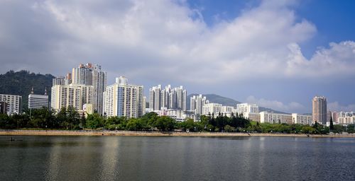 Sea by modern buildings against sky in city