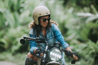 Woman with sunglasses sitting on motorcycle outdoors