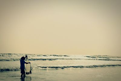 Man standing on beach against clear sky