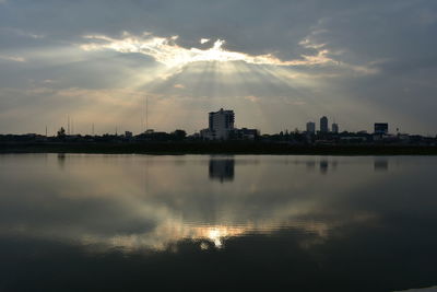 City at waterfront against cloudy sky