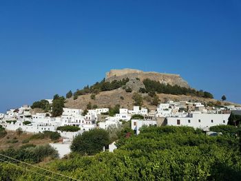 Houses on mountain against clear blue sky