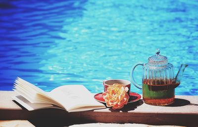 Book with tea and kettle by swimming pool
