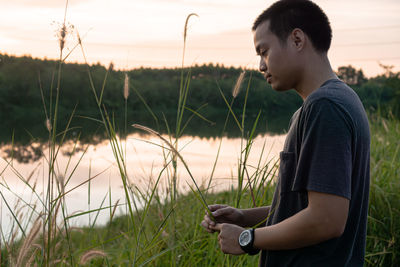 Side view of young man looking away on field