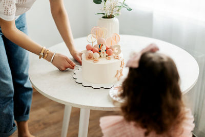 Mom cuts a piece of cake for her daughter during a birthday celebration at home