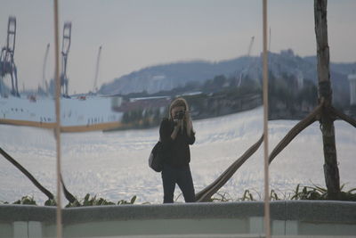 Full length of woman photographing on snow covered mountain
