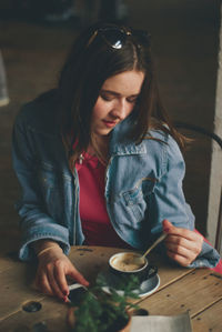 Young woman looking away while sitting on table