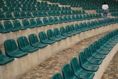 Rear view of woman standing by bleachers at stadium